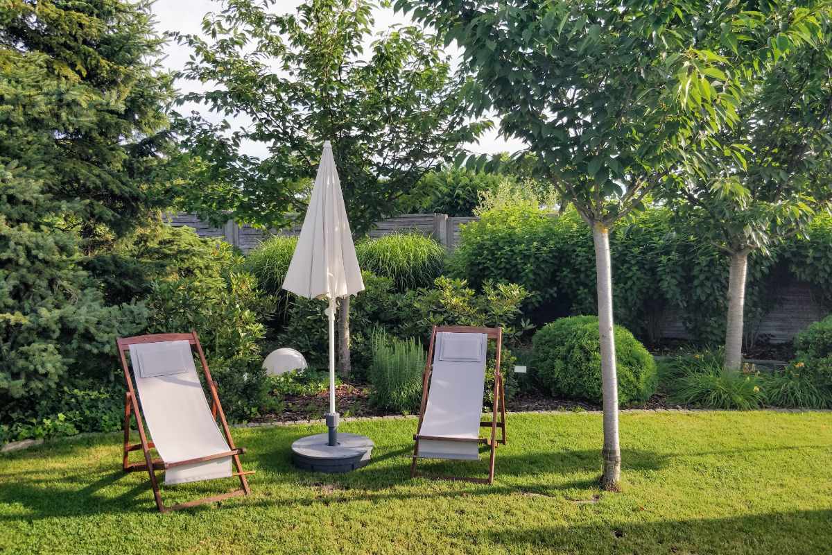 Vier Gärtner stehen gemeinsam in einer gepflegten Gartenanlage und lächeln in die Kamera.